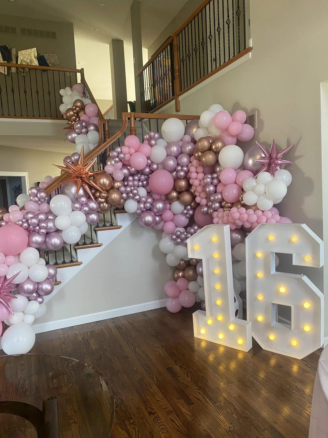 Pink, white and gold balloon staircase display for a 16th birthday with a lit 16 number sign