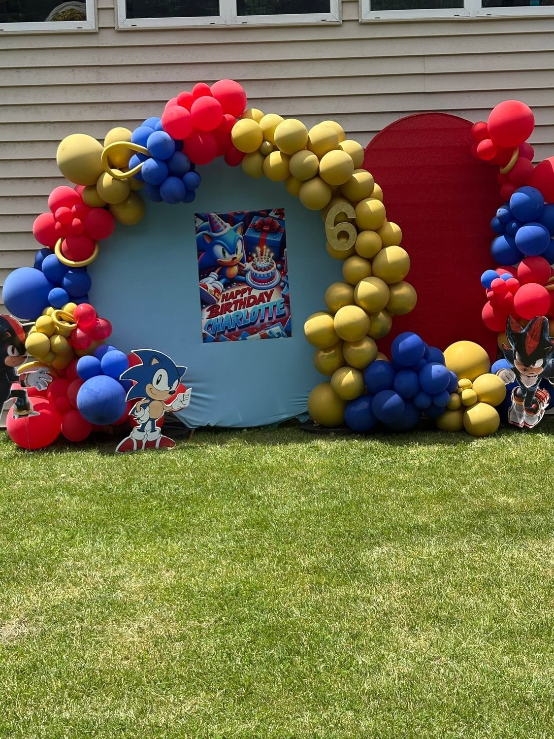 Sonic the Hedgehog themed outdoor balloon arch with red blue and yellow balloons and number 6